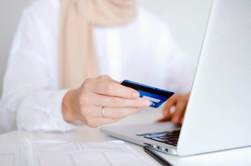 A person in a scarf paying their rent online with a card.